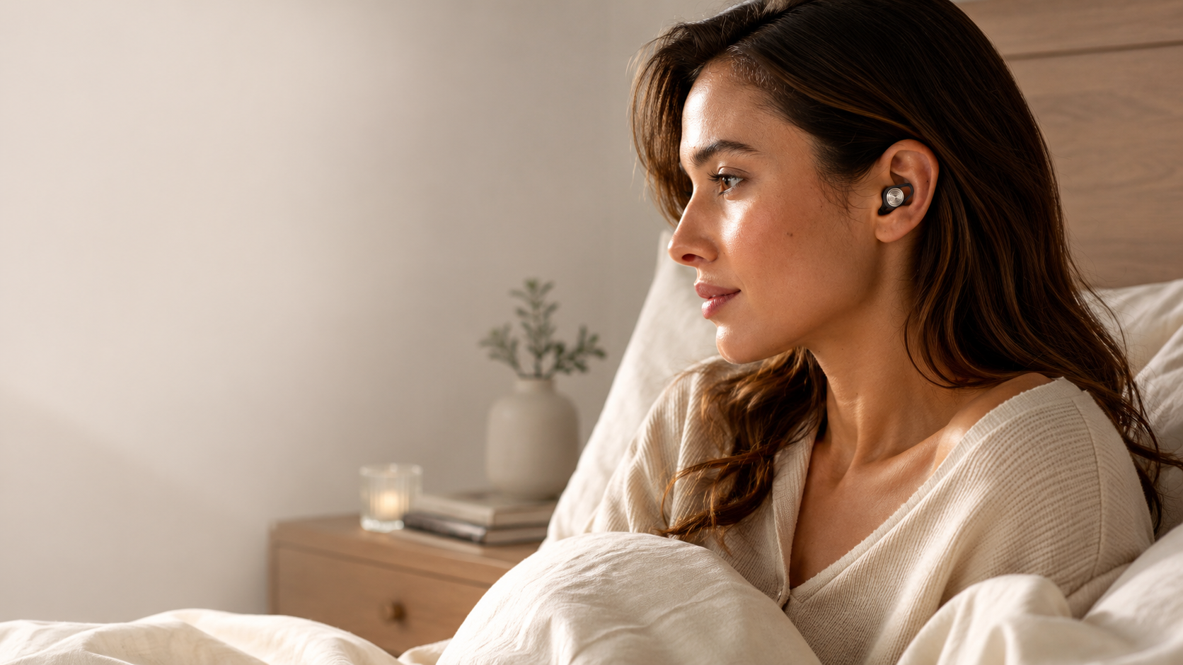 Woman resting calmly in bed wearing a Driftwell earplug